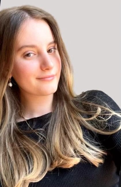 A woman with long hair and wearing black is smiling.